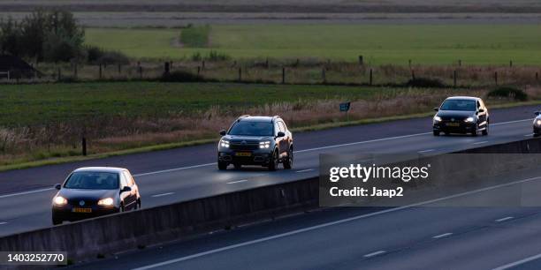 traffic (vw golf, citroen c5, vw polo) approaching on the a35 at sunset - volkswagen polo stock pictures, royalty-free photos & images