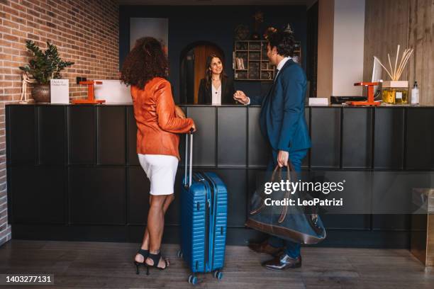 uomini d'affari che effettuano il check-in presso la reception dell'hotel - lobby foto e immagini stock