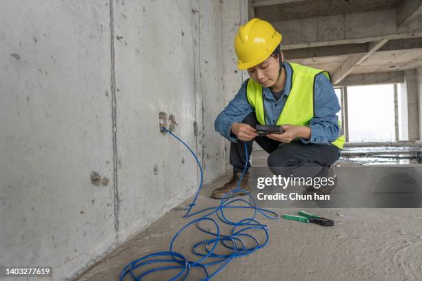 an asian female engineering technician carries out network wiring on the construction site - broadband stock pictures, royalty-free photos & images