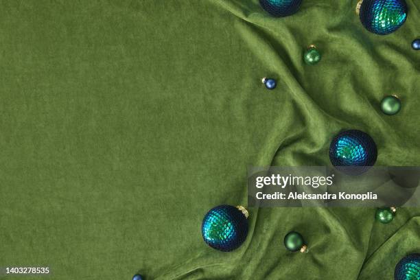 xmas still life background with dark blue and green christmas ornaments on folded green velvet - samt stock-fotos und bilder