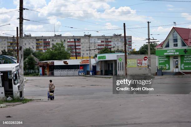 As a near constant boom from artillery fills the air, a woman carts water down an empty street on June 16, 2022 in Lysychansk, Ukraine. Residents...