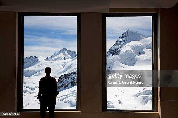 young man looking out windows. - jungfraujoch stock pictures, royalty-free photos & images