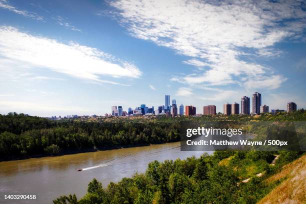 scenic view of river by buildings against sky,edmonton,alberta,canada - edmonton aerial stock pictures, royalty-free photos & images