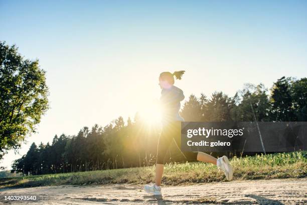 blick auf frau läuft auf feldweg - arid woodlands stock-fotos und bilder