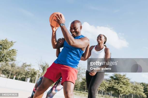 african family playing basketball together at sunny day - family health club stock pictures, royalty-free photos & images