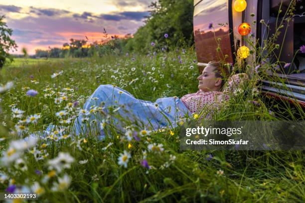 carefree woman relaxing over grass amidst plants outside camper trailer against sky - slovenia spring stock pictures, royalty-free photos & images