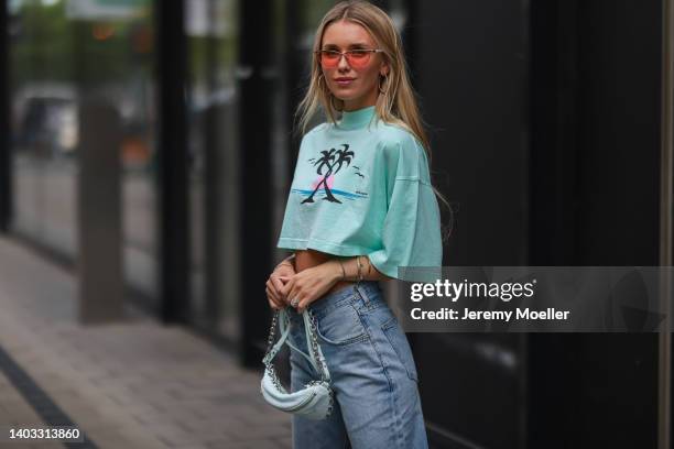 Scarlett Gartmann-Reus seen wearing a red sunglasses, a light green cropped Palm Angels shirt, a light blue wide leg denim jeans pants from Agolde...