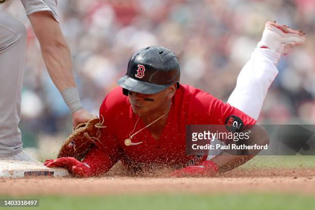 Rafael Devers of the Boston Red Sox dives into first base during the third inning against the Oakland Athletics at Fenway Park on June 16, 2022 in...