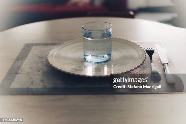 white plate with only glass of water on top - dining overlooking water stock-fotos und bilder