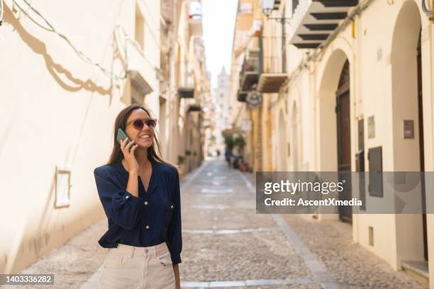 young woman explores  narrow streets, uses smart phone - blue blouse stock pictures, royalty-free photos & images