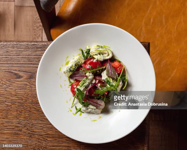 fresh summer vegan salad with tomato, cheese and arugula on wooden table in restaurant - plain salad stock pictures, royalty-free photos & images