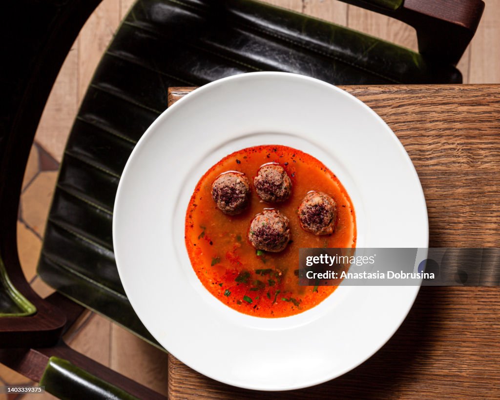 Tomatensuppe mit Fleischbällchen auf Holztisch im Restaurant