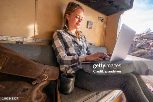 young adult business woman taking a break from exploring the area where she is camping to work for awhile, remote working while on vacation - laptop desert stock pictures, royalty-free photos & images