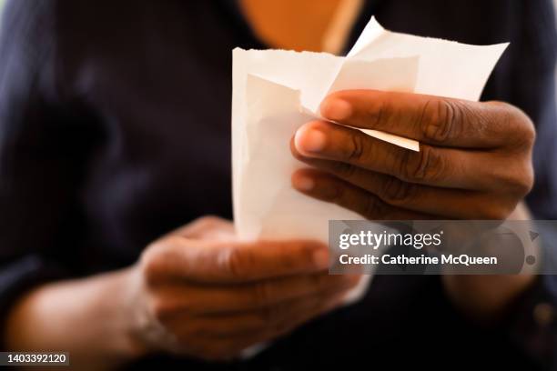 economy: black woman holding multiple retail receipts - bonnetje stockfoto's en -beelden