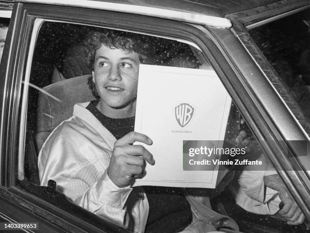 American actor Kirk Cameron sitting in the front passenger seat of a car, brochure in his hands, on which is the Warner Bros logo, as he looks out of...