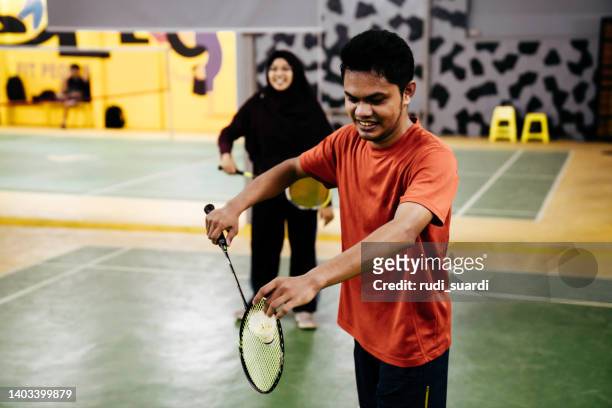 two couples playing badminton against each other on an indoor court. - mixed doubles stockfoto's en -beelden