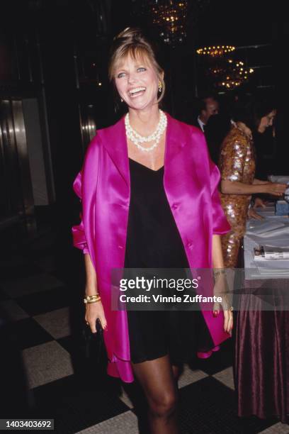 America fashion model Cheryl Tiegs, wearing a pink jacket over a black dress, attends an event, United States, circa 1995.