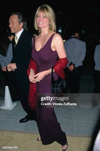 American fashion model Cheryl Tiegs, wearing a burgundy evening dress with a scoop neckline, with a red shawl draped over her arms, attends the 2nd...