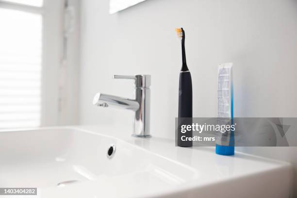 electric toothbrush in a bathroom - bathroom sink stock-fotos und bilder