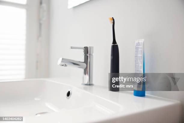 electric toothbrush in a bathroom - electric toothbrush stock pictures, royalty-free photos & images