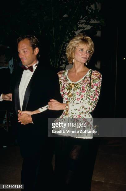 American actor Anthony Peck and his wife, American fashion model Cheryl Tiegs, wearing a floral pattern white jacket with a black skirt, attend the...