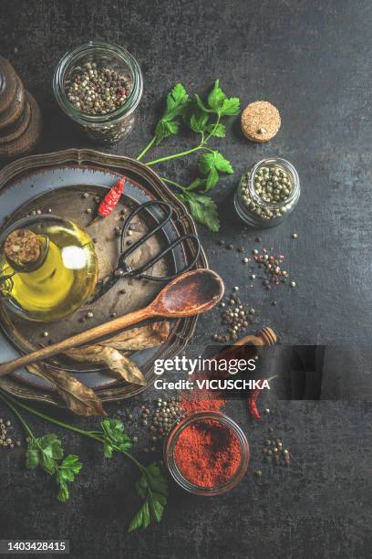 food background with flavorful ingredients: spices and herbs at grey concrete kitchen table with wooden spoon and olive oil. - ayurveda stock-fotos und bilder