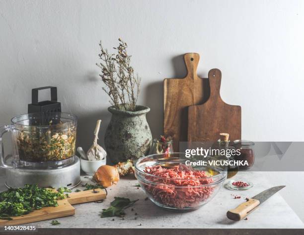 food still life with minced meat, herbs, kitchen utensils and food processor on grey concrete kitchen table at wall background - meatballs stock pictures, royalty-free photos & images