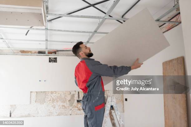 trabajador de la construcción instala techos de placas de yeso y aislamiento. techo de paneles de yeso - mildew fotografías e imágenes de stock