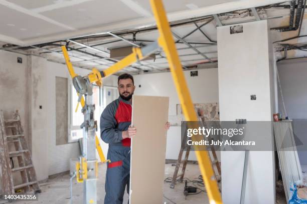 der bauarbeiter installiert gipskartondecken und isolierungen. trockenbaudecke - drywall stock-fotos und bilder