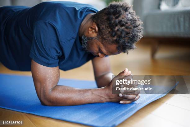 fuerte atletismo ajuste joven haciendo ejercicio en su casa - postura de plancha fotografías e imágenes de stock