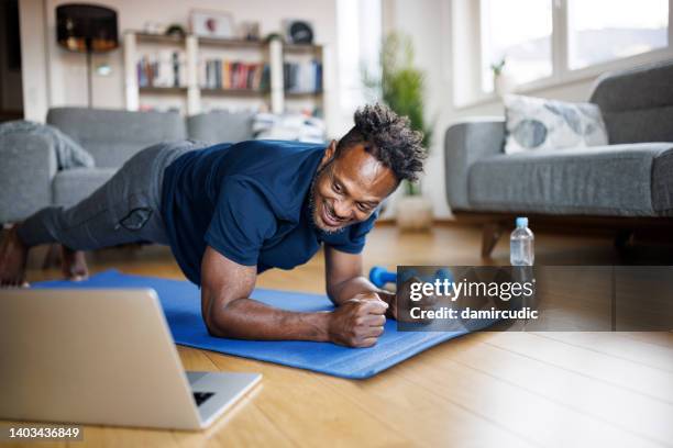 uomo sorridente che si allena a casa - plank exercise foto e immagini stock