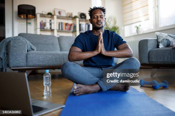 man meditating at home - lotus position stock pictures, royalty-free photos & images