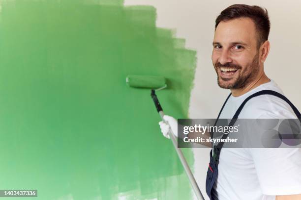 feliz pintor de casas pintando la pared de verde. - pintor fotografías e imágenes de stock