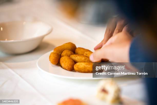 people taking croquettes of a plate. - kroket stockfoto's en -beelden