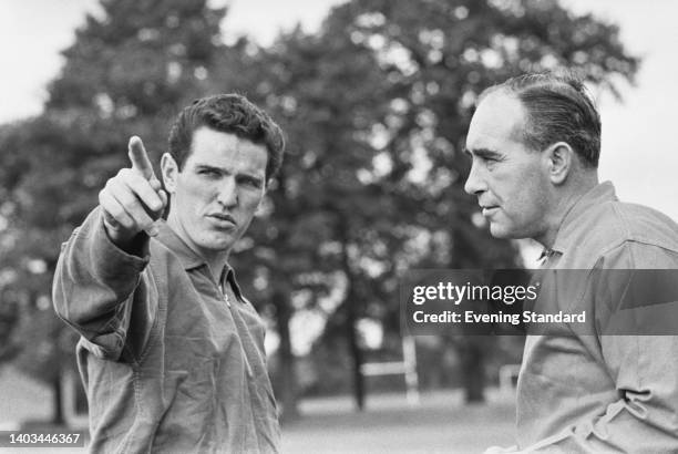 British footballer Terry Paine in conversation with British football manager Alf Ramsey , manager of the England team, during an England training...