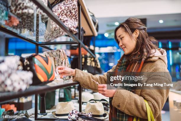 young cheerful asian woman shopping for accessories in boutique - purse bildbanksfoton och bilder