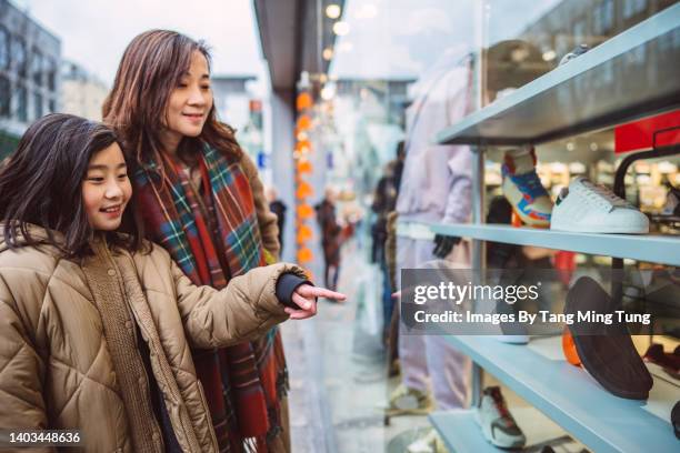 mom & daughter having window shopping in shopping street. - family shoes stock-fotos und bilder