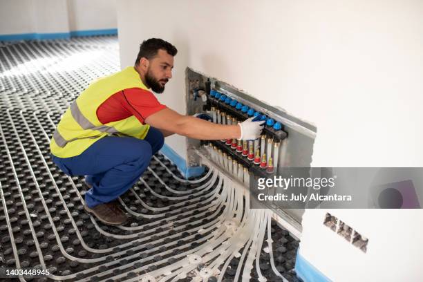 man installs and checks underfloor heating. floor heating system installation - flooring installation stock pictures, royalty-free photos & images
