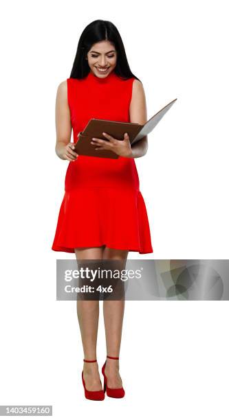 latin american and hispanic ethnicity young women standing in front of white background wearing dress and holding note pad - the x files stock pictures, royalty-free photos & images