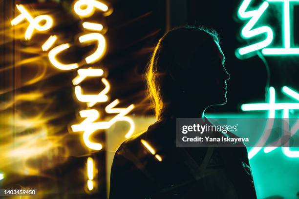 woman silhouette against neon signs at night - back lit signage stock pictures, royalty-free photos & images