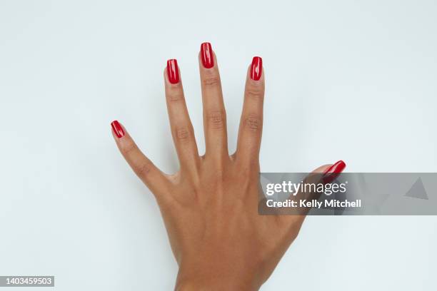 black woman manicured hand with red nail polish on white background - red nail polish stockfoto's en -beelden