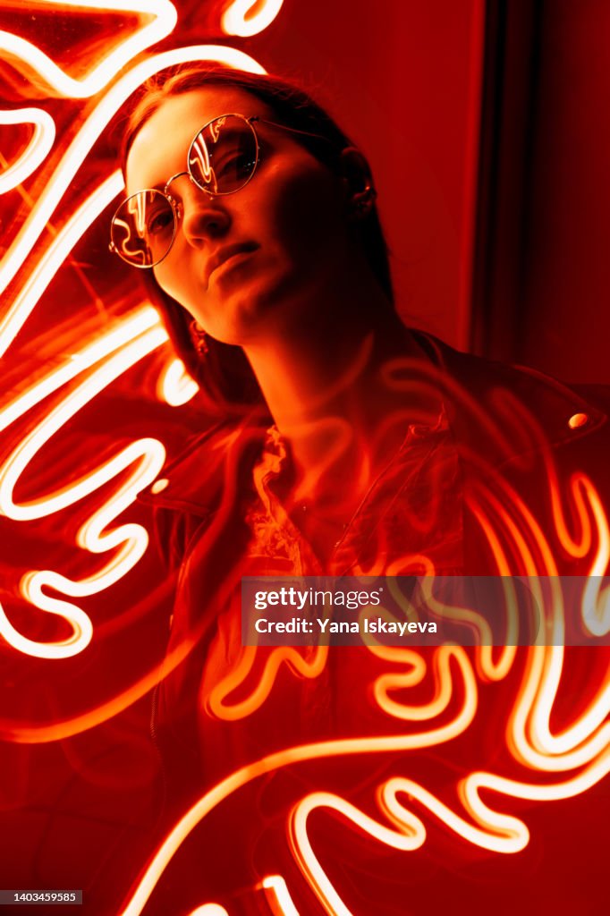 Portrait of a woman in glasses against red neon sign