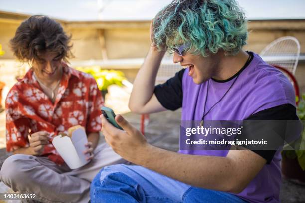gay teenage boy with half blue dyed hair taking selfie with mobile phone, on the rooftop - blue hair stock pictures, royalty-free photos & images