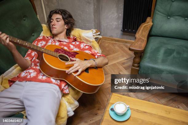 modern caucasian teenage boy playing acoustic guitar at the coffee shop - hipster coffee shop candid stock pictures, royalty-free photos & images