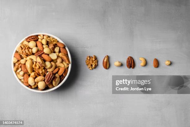 a bowl of mixed raw nuts with each nuts on the table - amendoim noz - fotografias e filmes do acervo