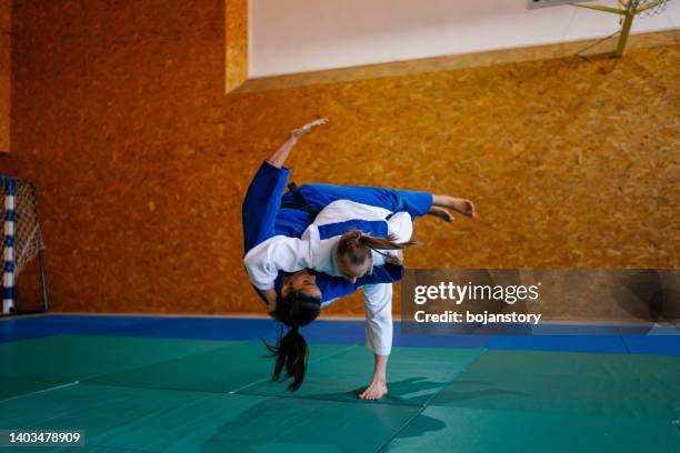 dos jóvenes luchadoras de judo que muestran habilidad técnica mientras practican artes marciales en un club de lucha - women's judo fotografías e imágenes de stock