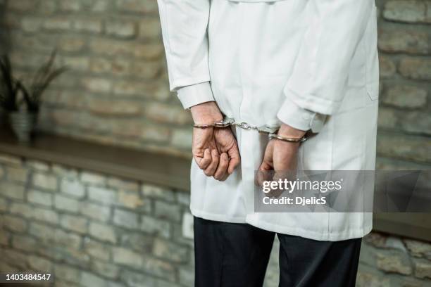 handcuffed male doctor getting arrested. - caught cheating stockfoto's en -beelden