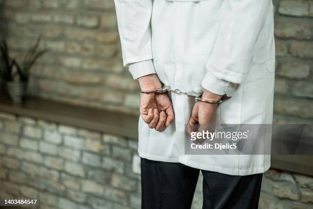handcuffed male doctor getting arrested. - restraining device stock pictures, royalty-free photos & images