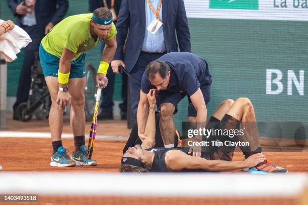 An injured Alexander Zverev of Germany holds his ankle after falling resulting in his retirement as Rafael Nadal of Spain looks on during the Singles...