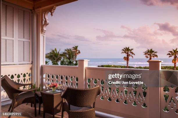 balcony overlooking ocean at sunet with two glasses of wine - luxe hiver stock-fotos und bilder